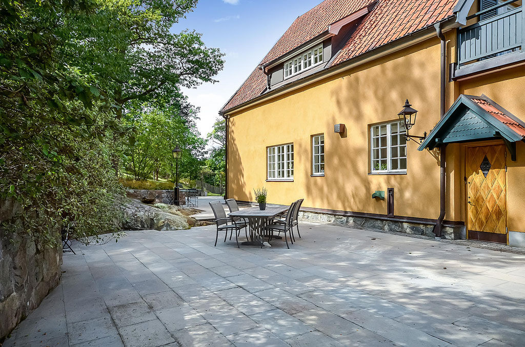 Stenlagd uteplats vid gult hus